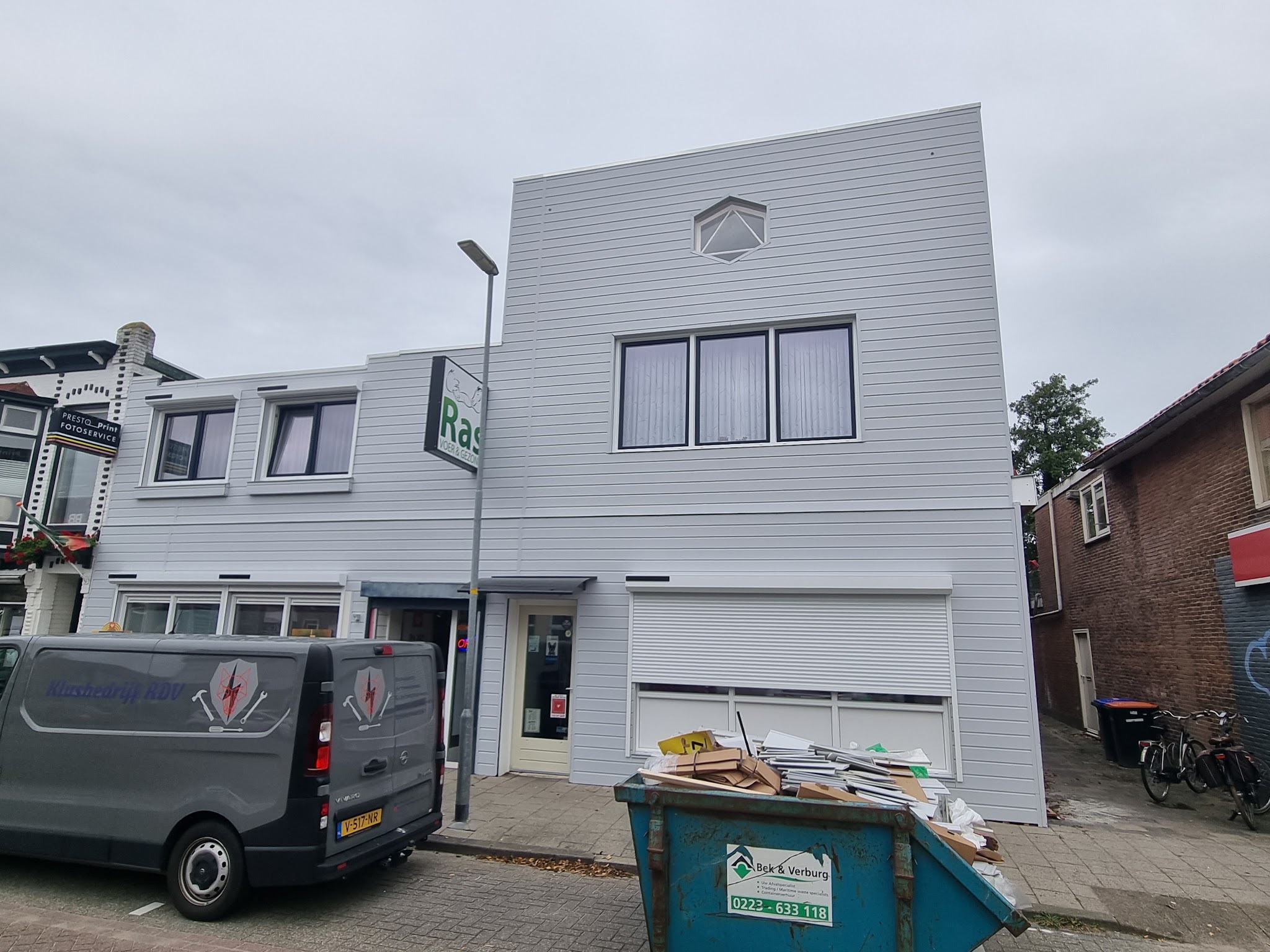 De bus van Klusbedrijf RDV en een container voor het pand van Ras Voer tijdens de klus